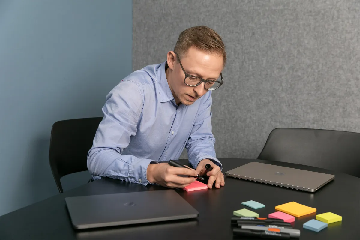 Christopher Ahlers plant am Tisch mit Notizzetteln
